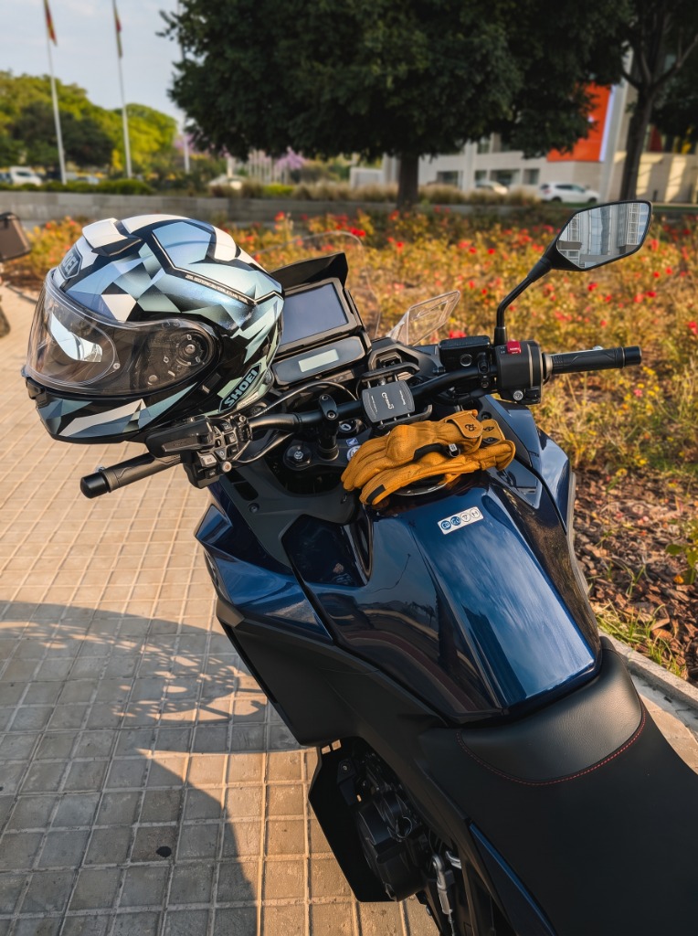 Moto de viaje con casco Shoei y guantes sobre el depósito
